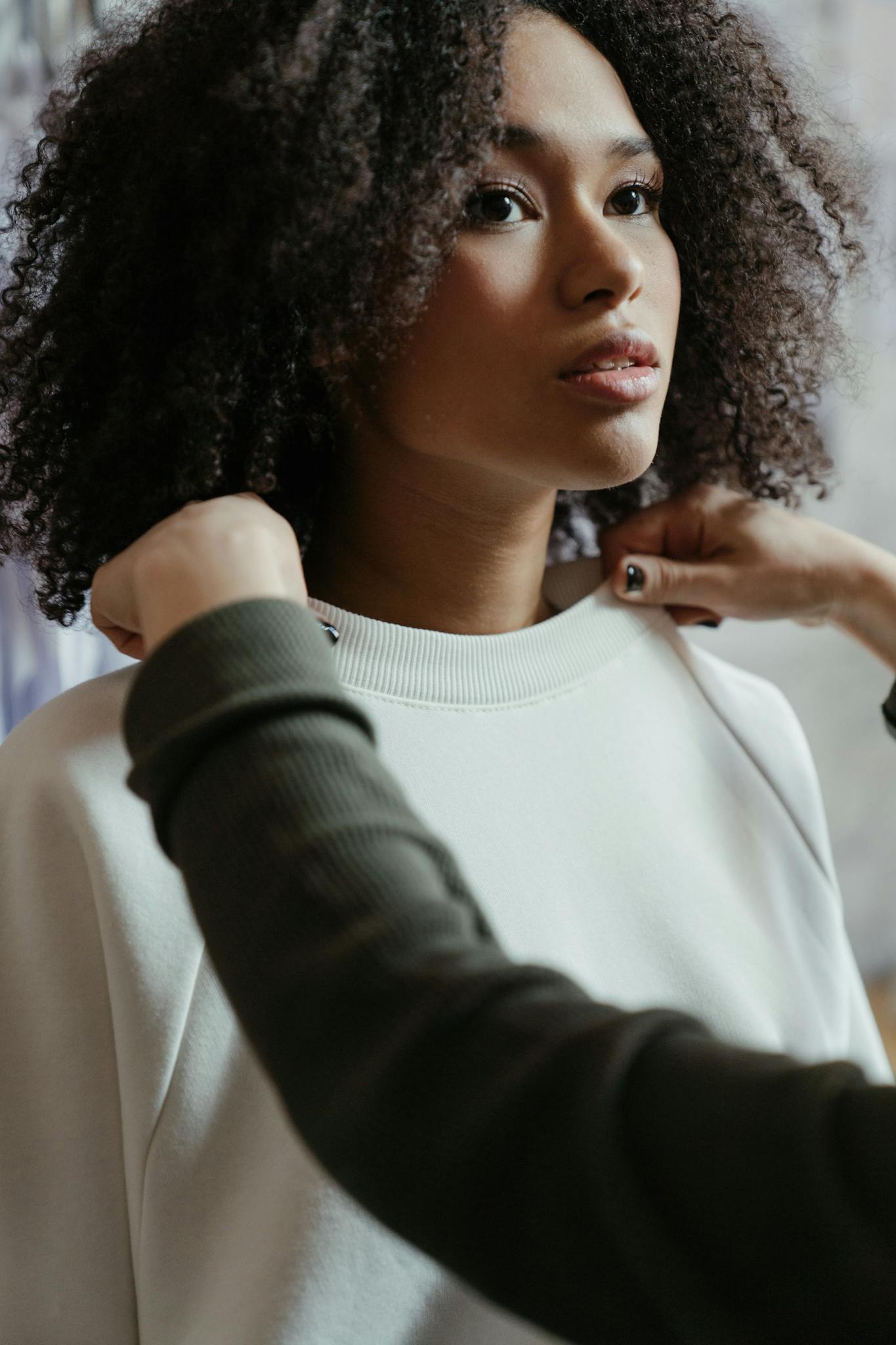 Fashion designer adjusts a model's outfit in a clothing studio.